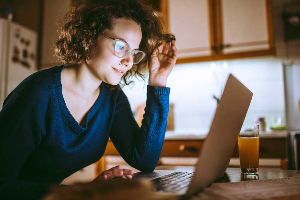 Young beautiful woman looking at the screen of a laptop and smiling